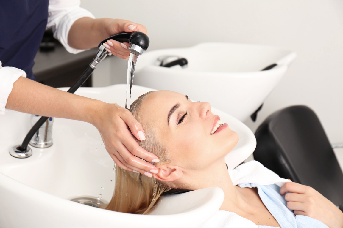 Hairdresser Washing Woman's Hair in Salon